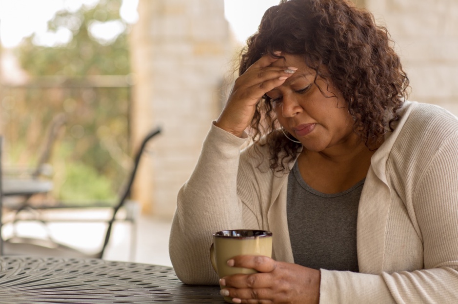 A stressed woman holding a cup of coffee.