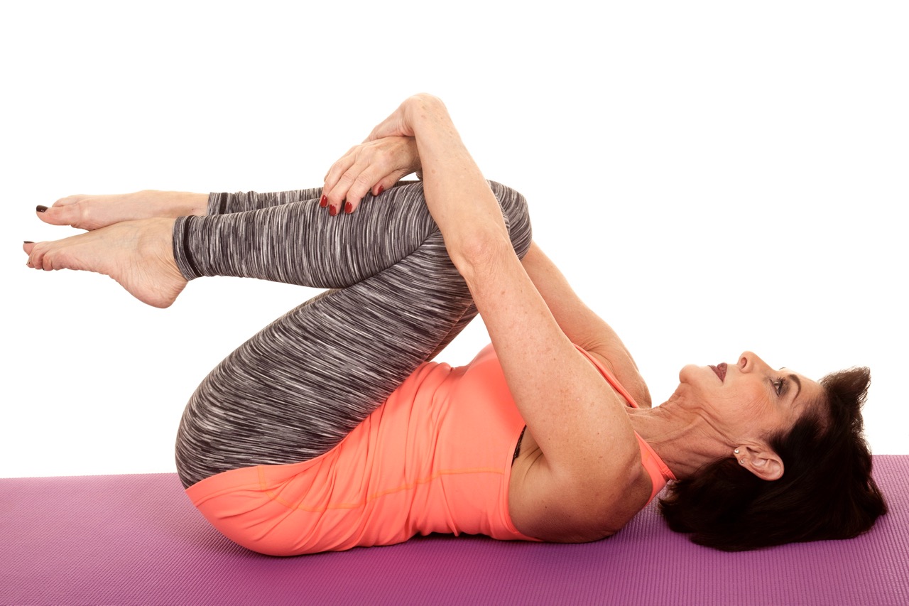 A person lying on her back on a mat