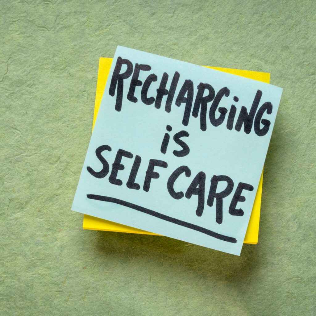 A note on a post-it saying recharging is self care.