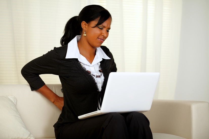 A woman with back pain on her computer