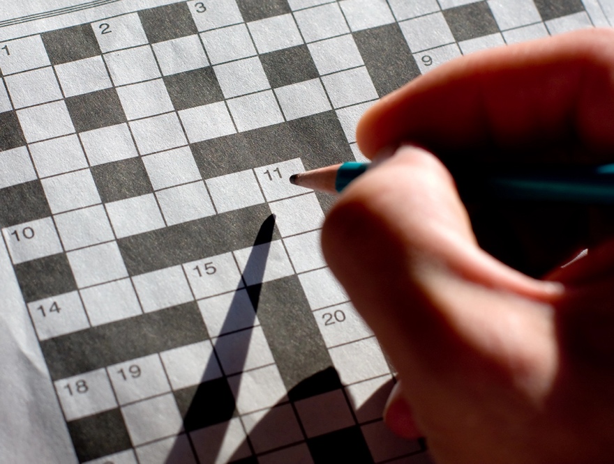 A person writing on a crossword puzzle